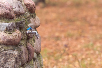 drain water from the tap Metal outdoors. Faucet in a natural stone wall