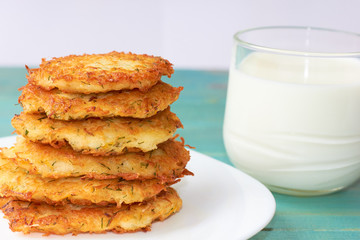  Appetizing potato pancakes and mug with milk on a wooden background