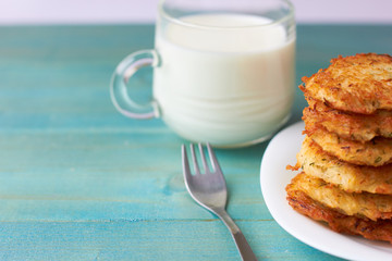  Appetizing potato pancakes and mug with milk on a wooden background