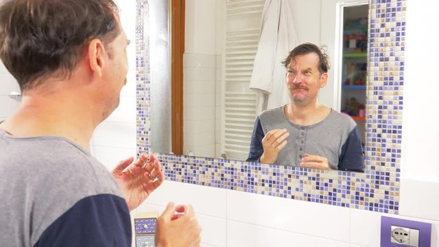 Man in front of mirror driving crazy about hair loss funny tracking shot