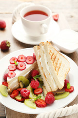 Toasts bread with various berries and cup of tea on grey wooden table