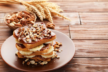 Toasts bread with bananas, walnuts and chocolate on wooden table