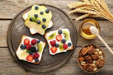 Toasts bread with berries on cutting board with various nuts