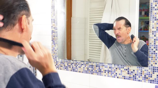 Funny man combing hair dancing funny in front of mirror closeup