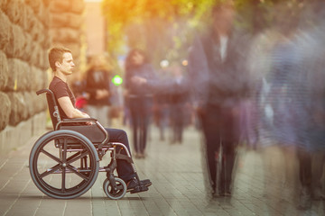 The invalid man sit in the wheel chair in the crowd stream at the pavement