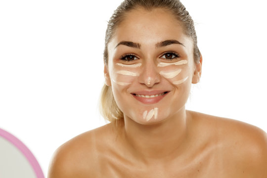 A young woman concealer a corrector under the eyes