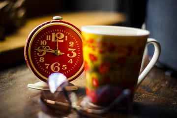  Still life with alarm clock and coffee cup, tea on wooden table.Good morning and start of new work...