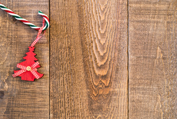 Candy cane with hanging vintage wooden Christmas tree on rustic wood plank surafce
