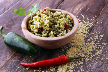 Bowl with homemade Bulgur Salad on wooden background.