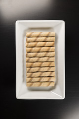White Plate With Waffle Rolls On A Black Surface