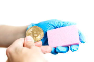 Hand with blue, medical gloves holding a golden bitcoin