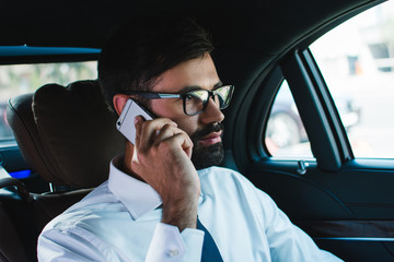 Perfect agreement is done. Handsome young man talking on mobile phone while sitting in car