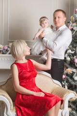 father, mother and a daughter on Christmas day near a beautiful tree