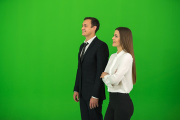 The business man and woman stand on the green background