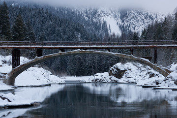 Obraz premium Winter Scenic With Bridge, Water, and Mountain