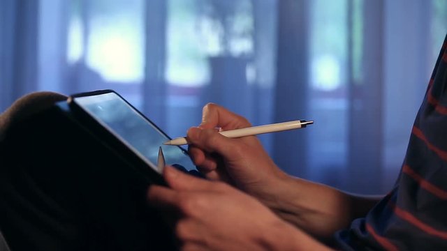Closeup shot of designer's hand drawing a picture using tablet with stylus at home. Artist make work. Painter is sketching.