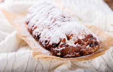 Dresdnen Stollen is a Traditional German Cake with raisins on a light knitted background.Gift for Christmas.Vintage style.Fruit cake for the Holiday. German, European festive dessert.
