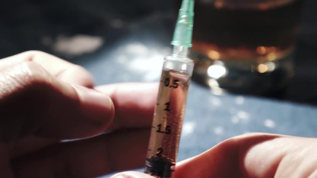 Extreme close up of man tapping heroin syringe
