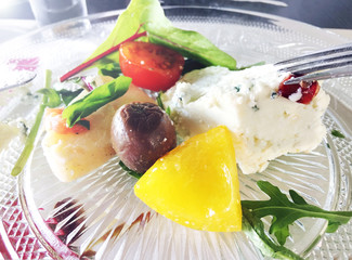 Breakfast with cheese, vegetables, greens and olives on a transparent plate