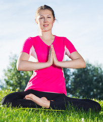 Sportswoman in pink T-shirt is sitting and meditating