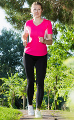 Sporty woman in pink T-shirt is running around