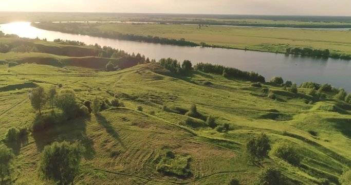 Journey through the Golden Ring. Drone flying under Orthodox cathedral, green meadows and a river bend. Russia, Konstantinovo village.