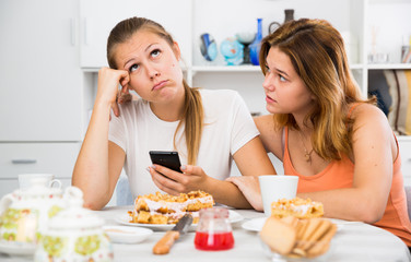 Obraz na płótnie Canvas Female talking with young sad friend with mobile