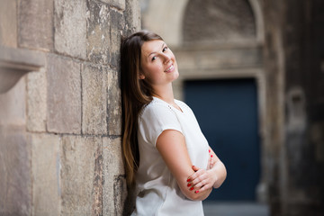 Romantic girl leaning against stone wall