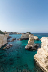 Sea stacks in a calm blue sea, with a blue sky as background