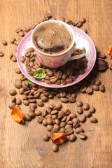 Coffee Cup on a wooden stand with scattered grains of natural coffee.