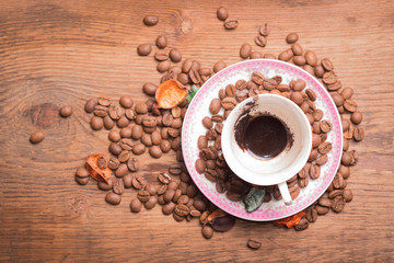 Coffee Cup on a wooden stand with scattered grains of natural coffee.