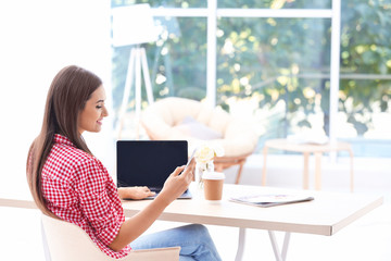 Young woman with laptop and cell phone at home