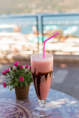 Delicious milk dessert with chocolate and strаwberry on ceramic table and blurred background