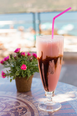 Delicious milk dessert with chocolate and strаwberry on ceramic table and blurred background