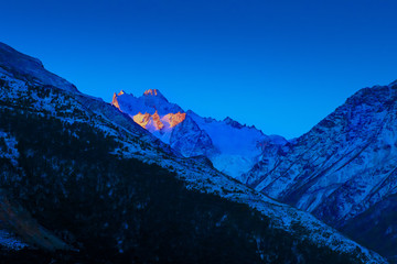 Fototapeta premium Bright sunset over blue Caucasian mountain peaks in winter morning dusk