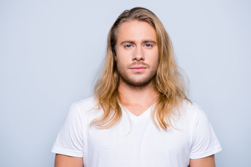 Portrait of handsome young serious confident young guy with blonde long hair in white tshirt, isolated on grey background - Powered by Adobe