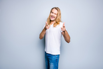 I choose you! Portrait of charming happy young guy dressed in casual clothes, he is giving a wink and indicating with his fingers, isolated on grey background