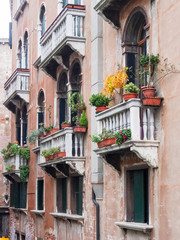 Fototapeta na wymiar Balconies, windows and flowers along a canal in Venice