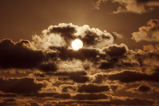 Romantischer Sonnenaufgang, Sonnenstrahlen leuchten orange durch Wolkenhimmel