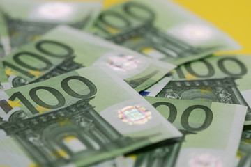 Obraz na płótnie Canvas Green hundreds of Euros spread on yellow background
