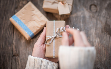Woman opening gift box over rustic wooden background