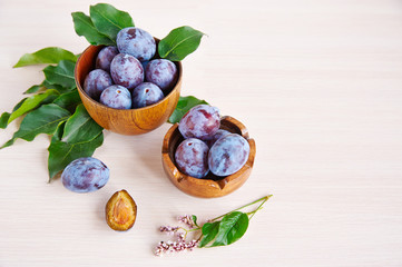 Prune in wooden cups on a rustic wooden table.