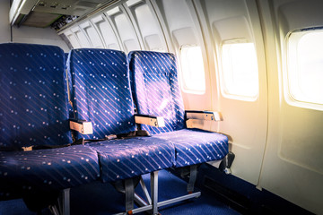 Seats in commercial aircraft cabin with sun light shining throug