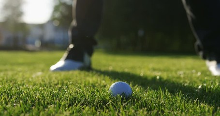 Close up of a moment when ball being strongly hitted by a club on the green golf pitch on a sunny summer day rising grass up. Outside. slow motion - Powered by Adobe