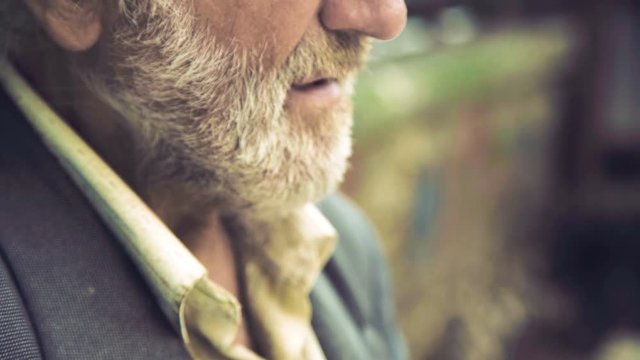 An old thoughtful man smoking a cigarette and looking aside 4K