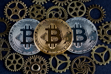 Three bitcoins among copper cog wheels closeup. Cryptocurrency concept.