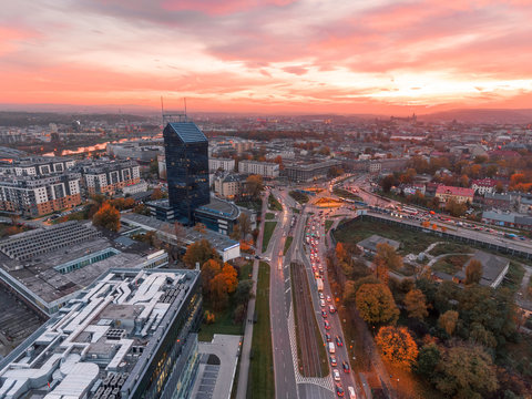 Modern architecture office building, Transportation, rush hour traffic, cars on highway interchange in city center. Sunset time, orange and gold light skyline. Drone aerial view of Krakow, Poland. 