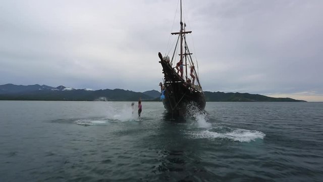 Tourists jump off yacht pirate ship on vacation.