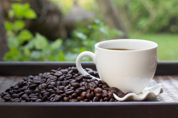 Coffee beans with white coffee mug blur background, A cup of hot coffee is placed beside the coffee beans