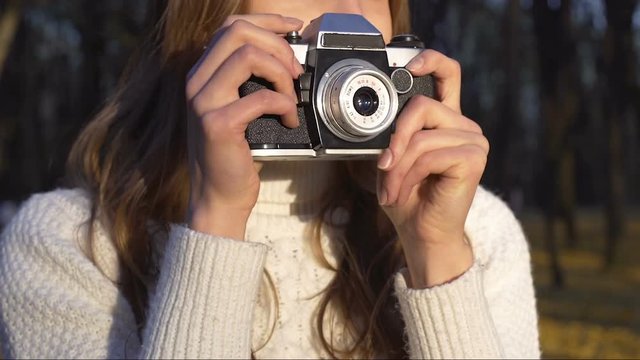 Talented girl taking pictures of beautiful autumn nature on old vintage camera